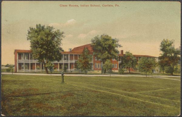 color image; view of the academic building, edited to give it the appearance of a red brick building; a fire hydrant appears in the foreground