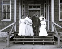 Seven students on steps of building [version 1], c.1900
