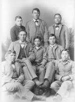 Seven male Crow students with John Nisely [version 2], c.1890