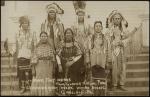 real photo postcard; a portrait of seven men and women, they stand on a set of steps, all of them are in regalia