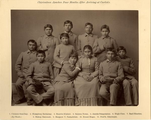 Studio portrait of eight male and three female students, all wearing school uniforms. 
