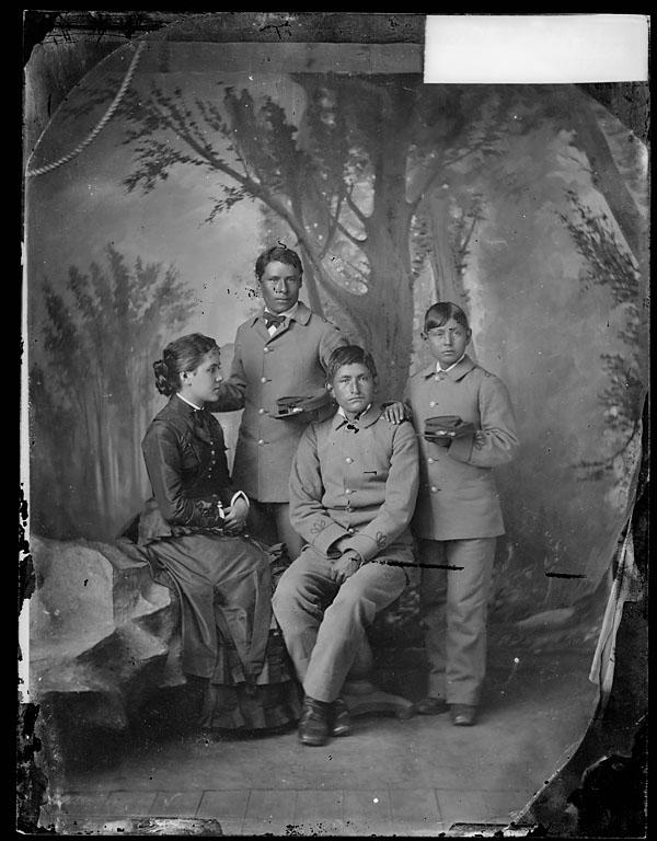 Three male Pueblo students with Miss Shields [version 1], c.1883
