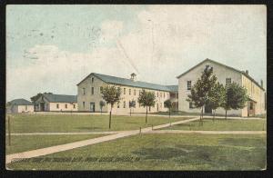a postcard showing a path leading to a U-shaped building with white walls (two stories) and blue roof