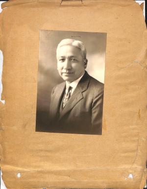 black and white photograph of a man in a suit and tie, smiling slightly