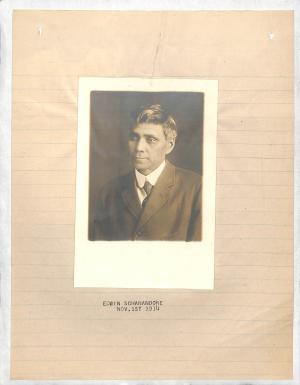 photograph of man looking to the right, wears suit and tie, short dark hair