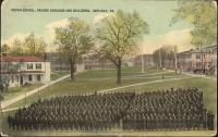 color image; view of the school grounds from perspective of the academic building towards the quarters, leaves have been painted onto the trees, in the foreground is a set of students arranged in tight rows (they are in black and white)