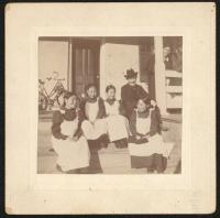 sepia photograph of four young women and one man sitting on steps, all of them are smiling