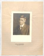 photograph of man looking to the right, wears suit and tie, short dark hair