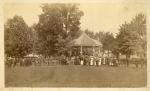 Line of visitors and band members in front of the band stand, c.1885