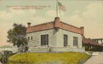 Alumni Hall, c.1908 color image; view of a building usually referred to as the art studio, a flag of the United States flies from a pole extending from the roof of the building, other buildings are in the background to the left