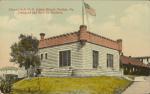 color image; view of a building usually referred to as the art studio, a flag of the United States flies from a pole extending from the roof of the building, other buildings are in the background to the left