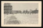 black and white image; view of campus from the teacher's quarters towards the large boy's quarters (facing northeast), the girl's quarters are just visible on the left and the superintendant's quarters just visible on the right, a few figures seem to run in the snow