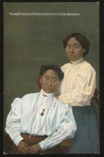 color image; portrait of two young women, one sitting to the left and one standing, the young woman sitting wears a white blouse with a necklace and pin, the young woman standing has pale yellow blouse and teal blue skirt, the background in green-brown