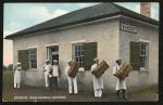 color image; six young men (presumably all students) stand outside building with "Bakery" sign, three carry loaves of bread