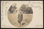 sepia image; in the center of the card is a photograhph a young man smiling, he is wearing a school uniform, the band stand is in the background, along the edges of the post card are handwritten words 